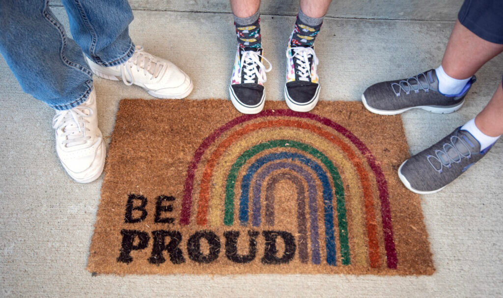 A Missouri family stands by their doormat at a home they are soon to leave — drawn out by bills that would limit the freedoms of their transgender son (Annelise Hanshaw/Missouri Independent).