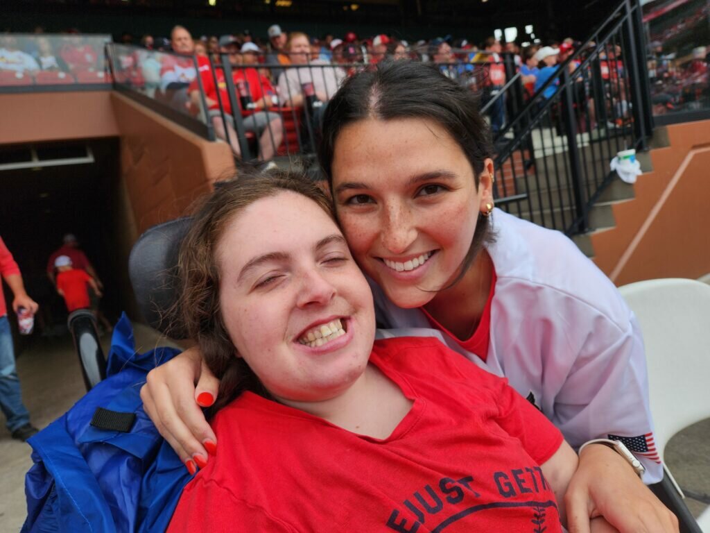 Lilly Opinsky, who has Rett disease, with her personal care attendant, Megan Wallis, at a Cardinals game this year. The family uses a program called self-directed supports to pay caretakers (Photo submitted).