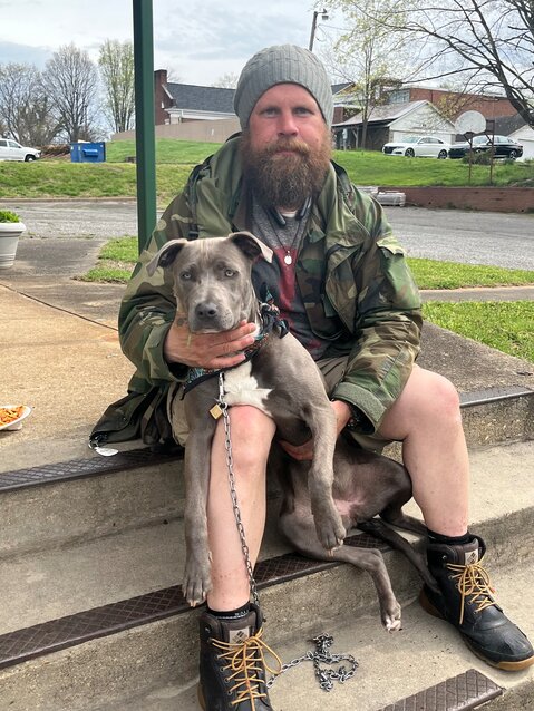 Eric Estes, known locally as Wolf, sits with his dog, Holly, on the steps at the Burke Museum of History on a recent afternoon. Wolf is one of Morganton's unsheltered residents.