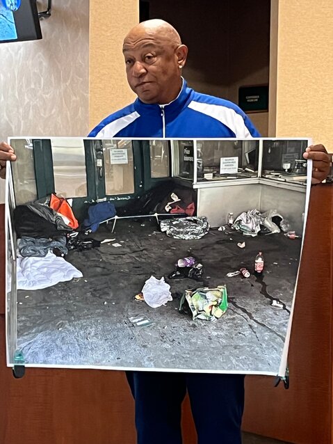 Ron Michaux holds up an enlargement of a photo he took on West Union Street that shows an area where homeless people have been staying. He said the streams of liquid on the right are urine.
