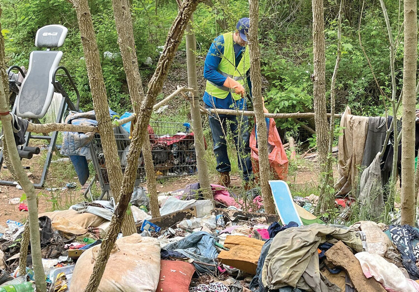 Revered Paul Carlson of Calvary Lutheran Church picks up trash at an abandoned campsite used by unsheltered folks. Community volunteers helped clean up portions of the site, located behind the Morganton Heights Shopping Center, in April. The problem of homelessness was The Paper's top story of 2023.