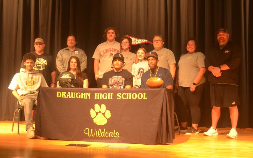 Draughn senior Nigel Dula on April 19 signed with Lenoir-Rhyne University to play football. Seated with Dula are his brother Mason Lytle, his mother Dawn Branch, and his father Seth Dula. Standing (from left to right) are Draughn assistant football coach Chris Cozort and Draughn athletic director Eric Shehan, Tristan Hines, Michelle Hines, Allena Hines, and Dula's middle school coach Stephen Hines, Draughn athletic trainer Ali Miller, and Draughn head football coach Chris Powell.