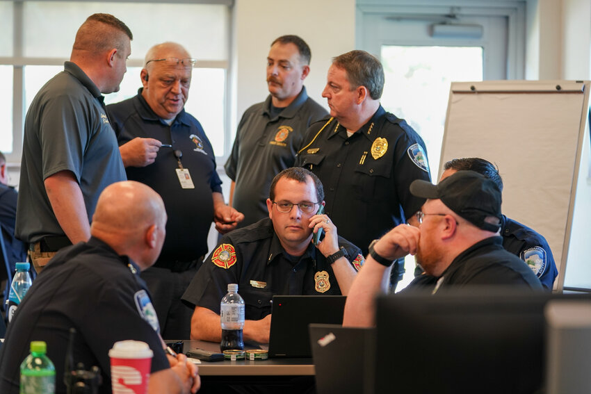 Emergency Management Director Mike Willis (holding pen) with law enforcement leaderships discuss the progress of the emergency exercise.