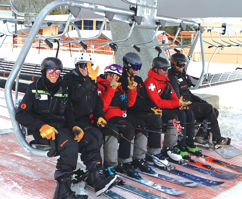 Mountain crew ready to rideSki patrollers and mountain staff flash smiles and peace signs as they load the lift in full gear.
