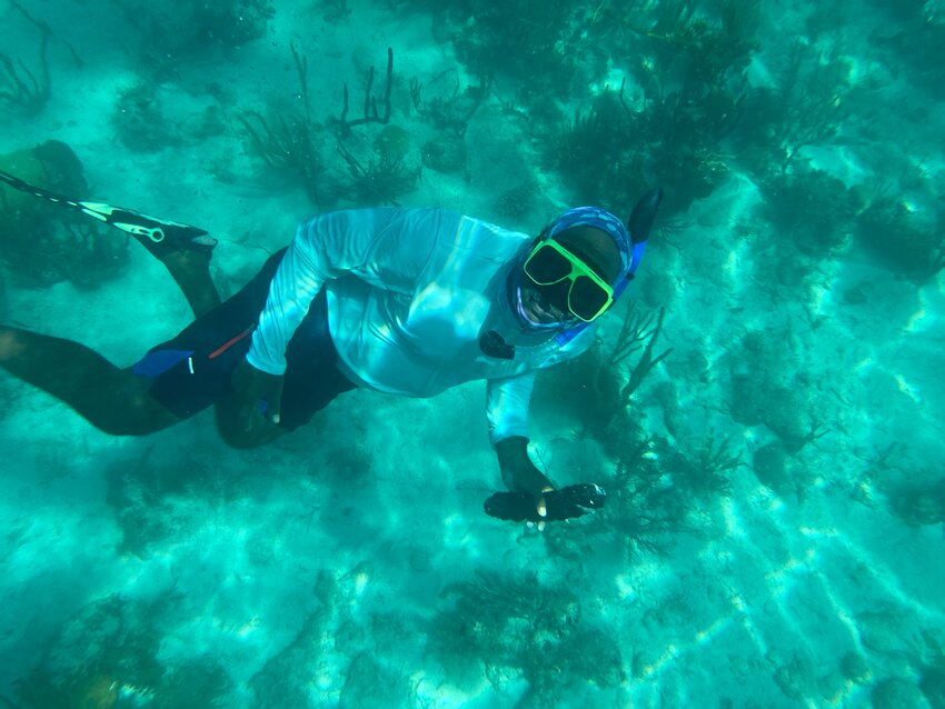 Jason Williams fetches a sea cucumber from the sea bottom at Mojo Caye, Belize.