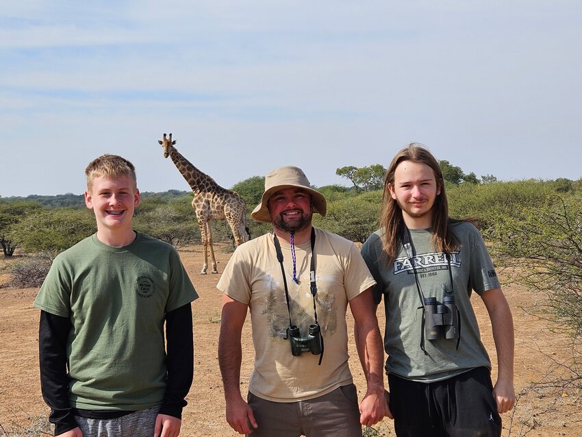 (From left): Landen McDonough, Nathan Winger and Luke Battaglia with a giraffe in the background.