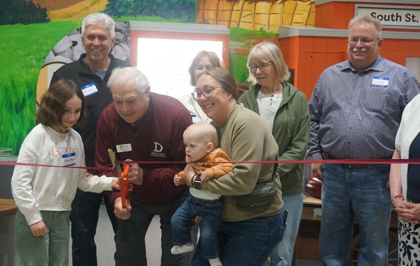 Dakota County Historical Society President Steve Cook, alongside relatives and descendants of Fred Lawshe cut the ribbon on the newest permanent exhibit at the Lawshe Memorial Museum: The Curiosity Collection.