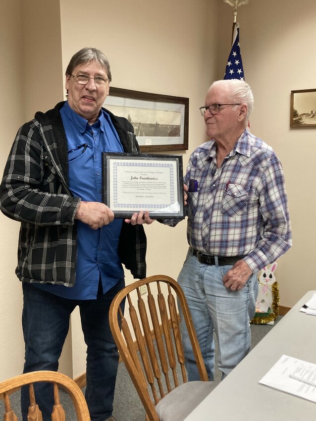 John Frankewicz receives a plaque for his 18 years of service on the Withee Village Board from board president Everett Lindgren. 