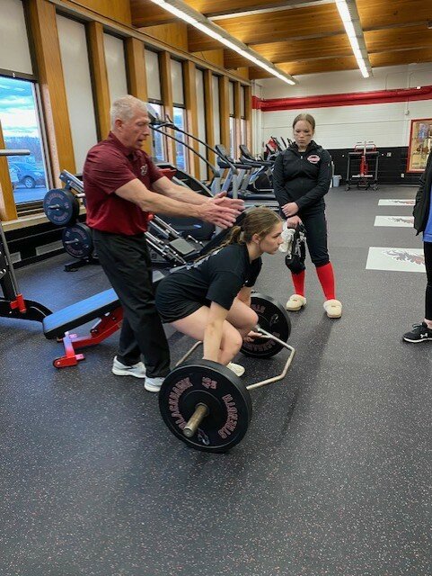 Coach Terry Laube explains the correct stance for lifting as Kayla Rasmussen demonstrates. 
