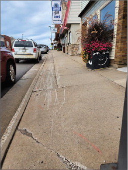 This portion of sidewalk, extending from the new library at 388 W. Main St. to Chestnut Street, is one segment that will be replaced by Pember Companies. Photo by Sarah Nigbor