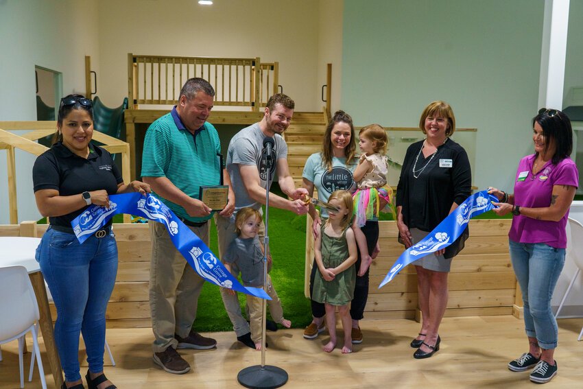 Ryan and Laura Fritz are surrounded by their kids, city officials and members of the Cottage Grove Area Chamber of Commerce to celebrate the ribbon cutting of their new space, The Little Village.
