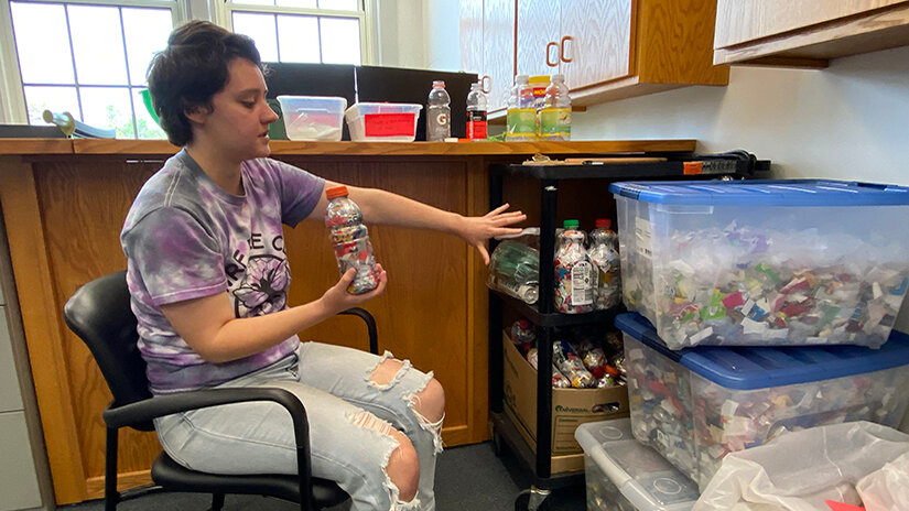 UWRF senior Amber Rappl explains how she and other students who work in the campus Sustainability Office create plastic bricks as part of recycling efforts.