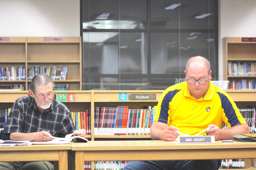 Above, School Board members Lanse Carlson (left) and Bob Geist read from self-assigned homework &quot;Schools Can't Do It Alone&quot; by Jamie Robert Vollner. The Board will hold a public budget hearing Oct. 24 on the 2023-24 budget.