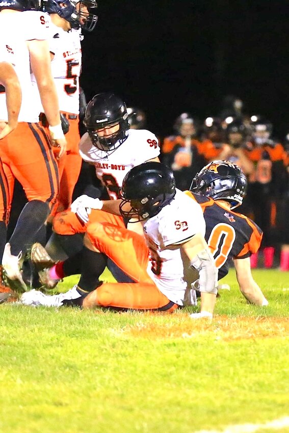 Above, Aaron Sturm (9) gets up from the tackle as brother Chase Sturm (40) sits after assisting, with Storm Tiry (50) also helping on the play.