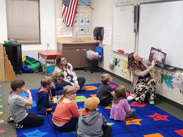 Kindergarten teacher Elizabeth Esslinger reads a story to students and their families during Fall Family Literacy Night at Stanley-Boyd while fellow Kindergarten teacher Becky Isenberger guides students in story comprehension.