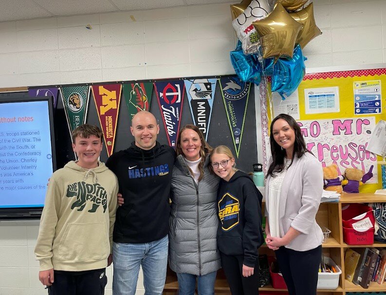 Kristy Barse, president of the Hastings Area Chamber of Commerce &amp; Tourism Bureau (pictured at right) surprised Kyle Kreuser in his Hastings Middle School classroom with his family last week to let him know he is being honored as the 2023 Educator of the Year.