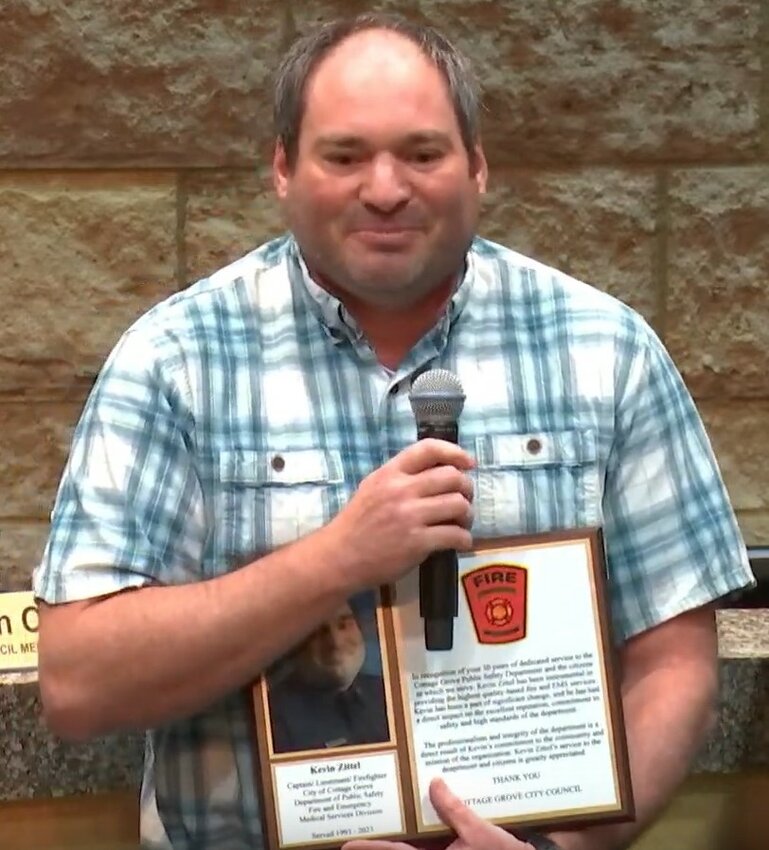 Kevin Zittel holding a plaque honoring his 30 years of service to Cottage Grove.
