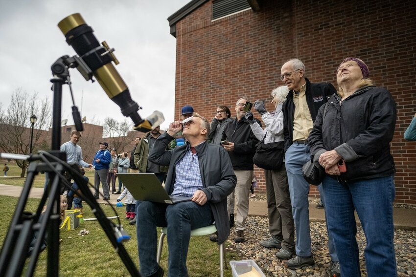 UW-River Falls Physics Professor Glenn Spiczak, seated, looks at the solar eclipse through a protective shield Monday afternoon with other faculty, staff, students and community members. Overcast skies spoiled the view for most in the upper Midwest, but the event still brought out many to Centennial Science Hall to catch a glimpse of some change in the sky and learn more about the phenomenon.