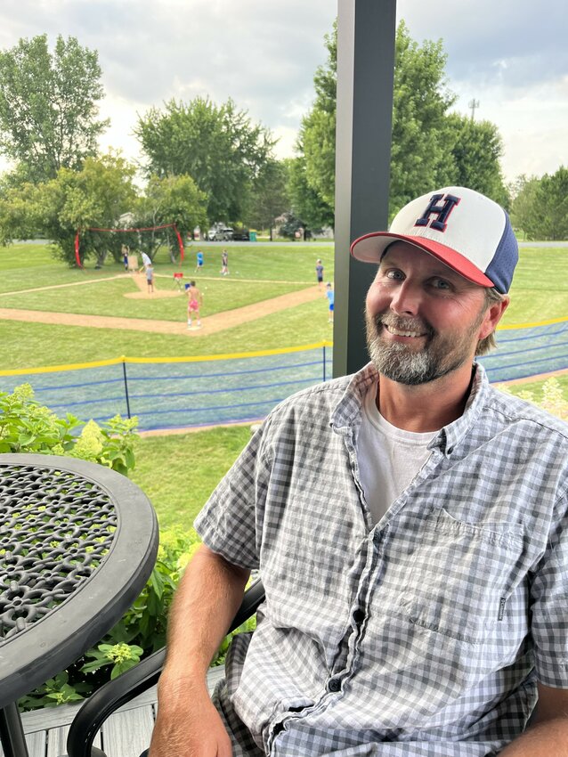 Dave Meyer sits on his porch watching his sons and friends play Wiffle Ball on their newly constructed Waffles Field.