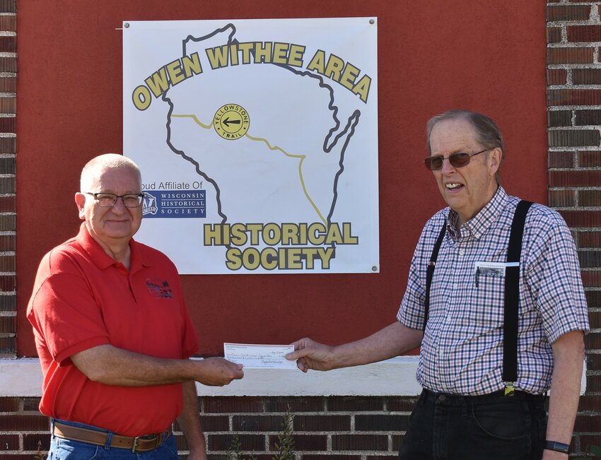 Owen Mayor Scott Jalling accepts a donation from Owen-Withee Area Historical Society treasurer Craig Scheinost. The money came from funds raised in the ice cream stand at the History Center during the Owen Main Street Car Show.