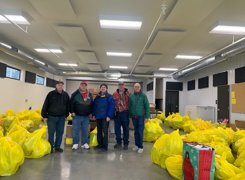 Stanley Lions members Carl Edwardson, Larry Ciokiewicz, Norm Christianson, Tim Troyer, and Gary Krueger standing in front of the many presents