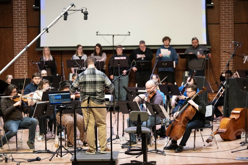 UW-River Falls student composer Sam Nesbit, at the podium, guides a concert band of student and community musicians during a daylong cinema scoring event in Abbott Concert Hall. Nesbit and fellow students Ben Garcia and Landon Zientara wrote original music compositions to some of their favorite videogames and the gathered musicians performed them in time with key sections of each game.