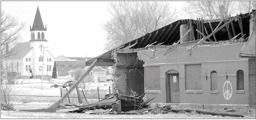 The 1906 Stanley railroad depot had its most recent roof ripped off by the tornado of December 15, while in the background stands the Stanley Church of the Brethren, which escaped visble damage in last Wednesday's storm.Photo by Joseph Back.