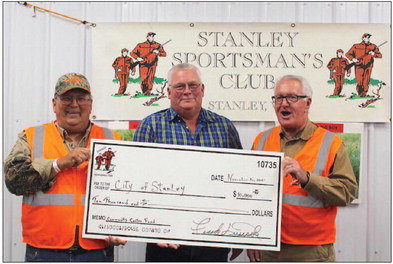 Donating $10,000 to the Community Center fund this November 13 on behalf of the Sportsman’s Club were Frank Dusick (left) and Butch Plombon (right), while Mayor Al Haas (center) accepted for the city. Funds from the night more generally went to area parks. Photo by Joseph Back.