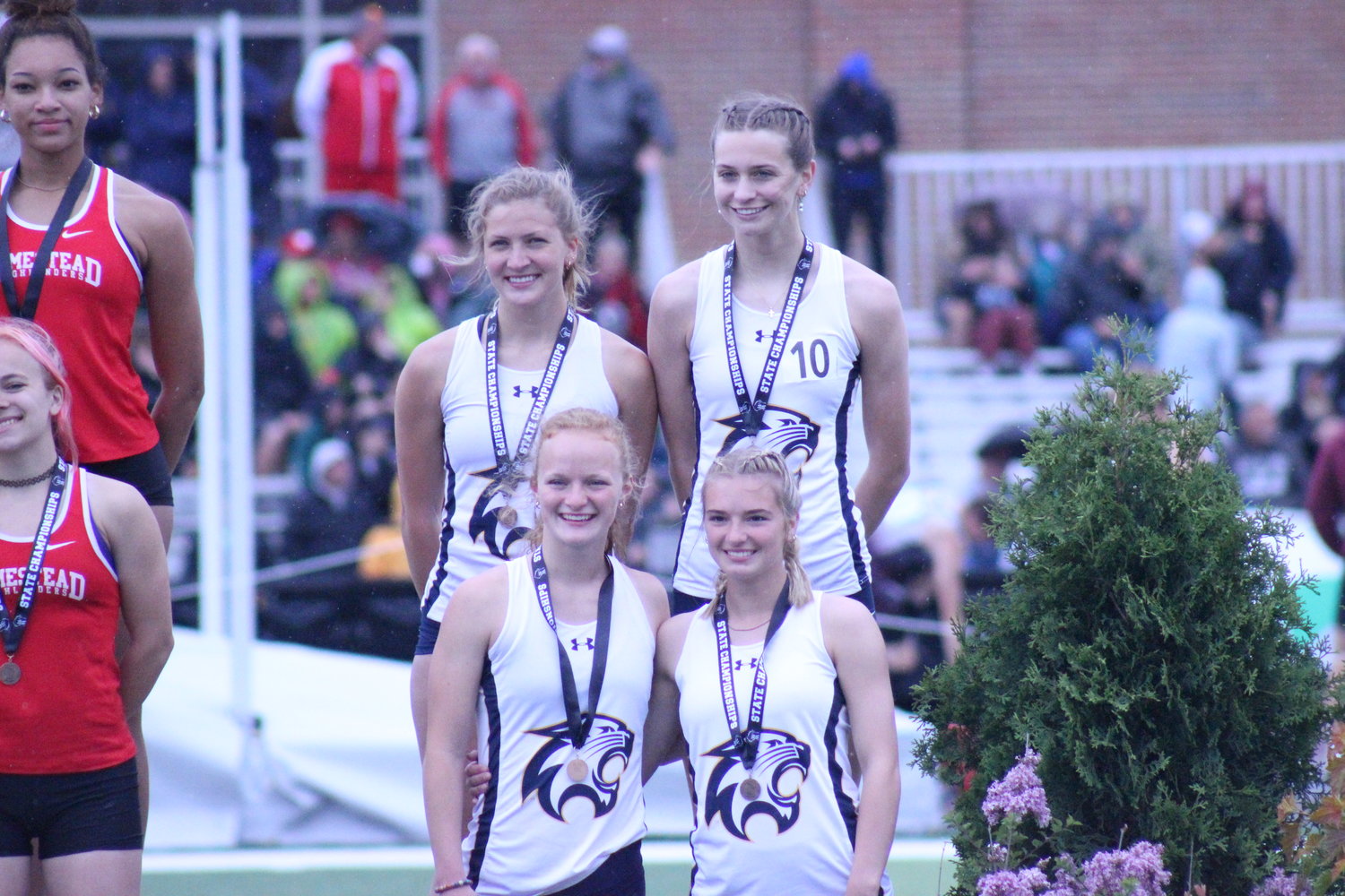 Seniors Elise Frisbie, Morgan Priggie and then-juniors Brooke Silloway and Rebecca Randleman wear their medals on the podium after finishing fifth in the Division 1 4x200 meter relay at the state championships in La Crosse last spring. Both Silloway and Randlemen return for their senior seasons this year.