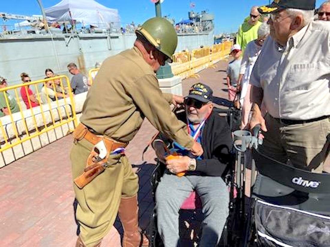 A military reenactor dressed as General Patton presents Stanley Korean War veterans Fred Wisniewski and Jack W. Caswell with medals.
