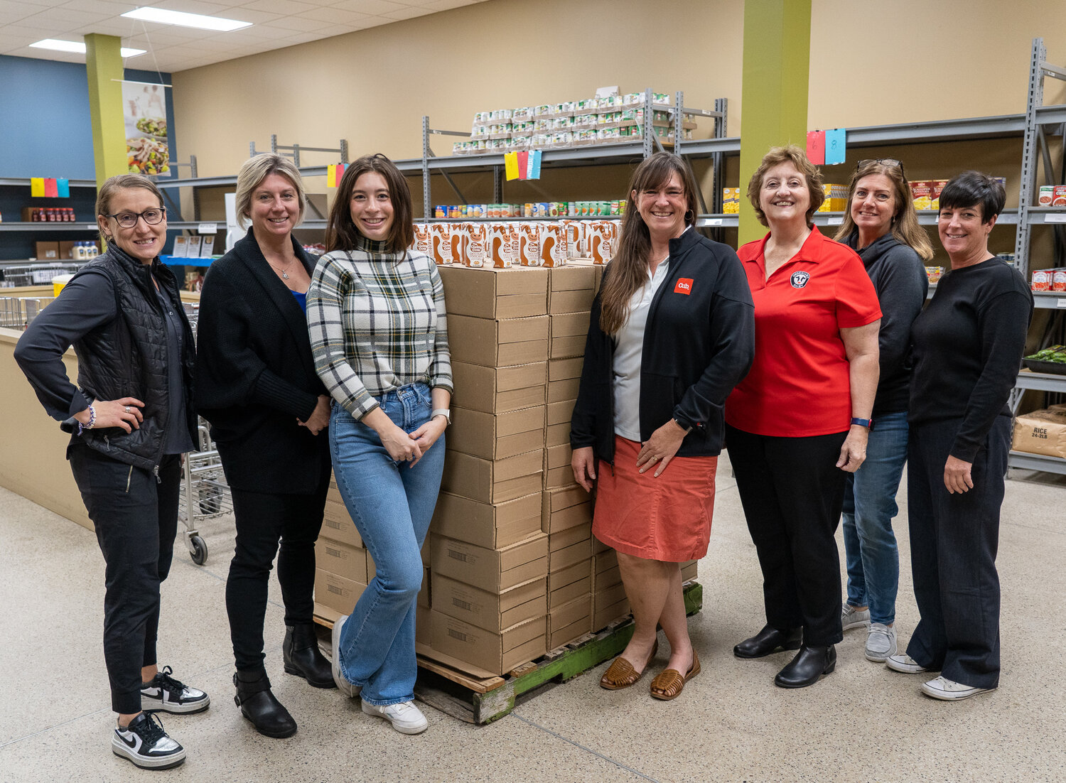 A group of representatives from Hastings Family Service, Cub and the Dairy Farmers of America pause in front of one of the pallets of Giving Cow milk that is stationed inside of the food pantry at Hastings Family Service. The chocolate milk will be a welcome, special treat for families this holiday season. L to R Amy Schaffer, Christina Taylor-Haley, Jayme Harlander, Tara Tommes, Janet Bremer, Amy Sutton and Deana Dunning.
