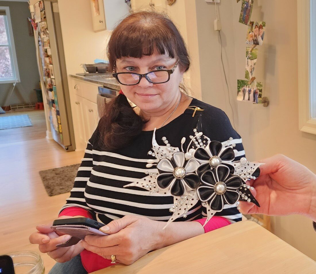 Valentyna Benson, the stepmother of Ellsworth educator Melinda Casper, sits at Casper’s kitchen table communicating with a translation app. The bow is one of many that she crafts and sells to raise money for her family in Ukraine.