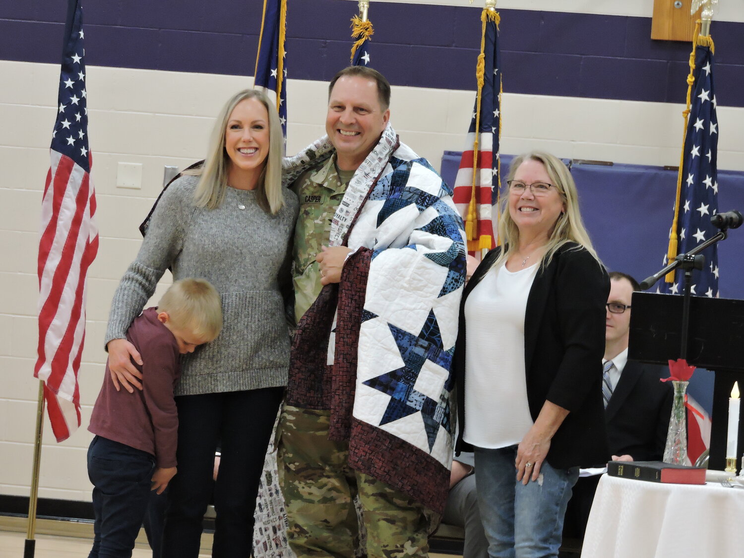 Lt. Col. Ryan Casper, wife Melinda Casper, and their son Raleigh wrapped in the Quilt of Valor, made and presented by Laura Cutsforth.