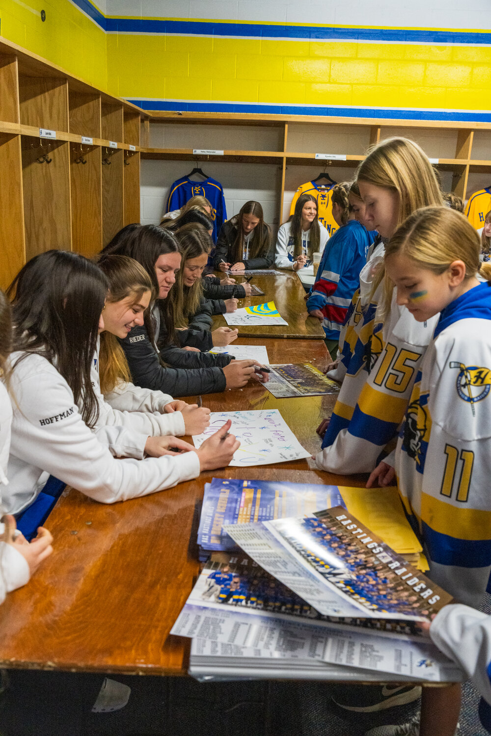 The varsity girls gathered in the locker room with team photos available for the youth hockey players to have for autographs during a meet and greet on Girls Hockey Day.