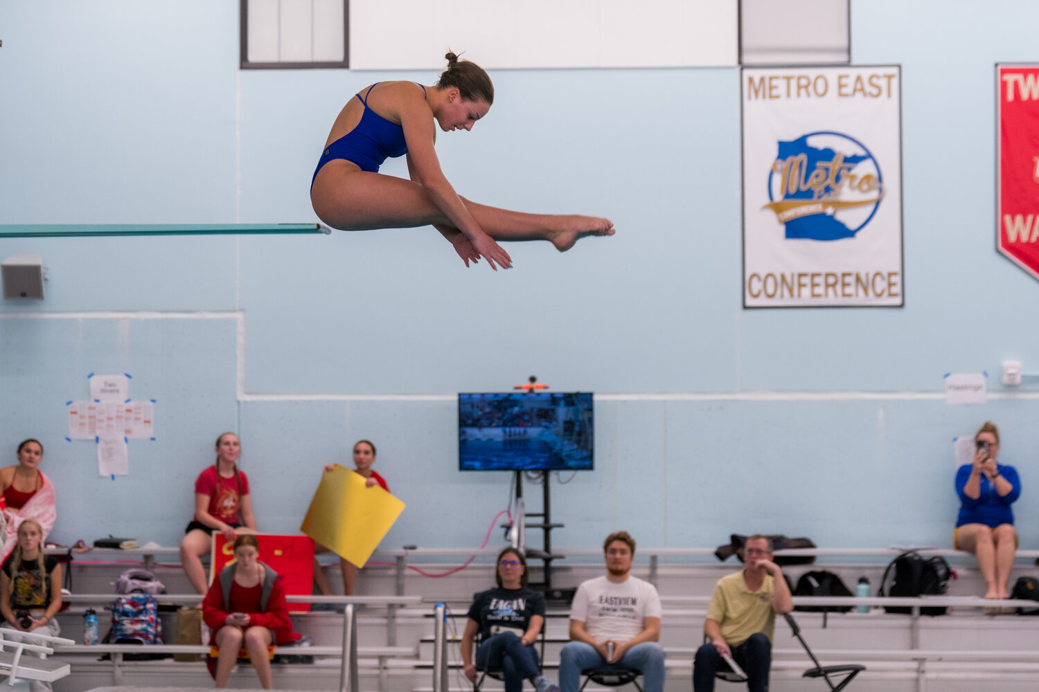 Aarness
Freshman Chloe Aarness took the Section 3AA diving title with a total score of 375.95. Here she is in the pike position perfectly in line with the 3-meter diving board. Aarness soared over the competition with her height off the 1-meter board in all 11 dives. Head Coach Katie McAlpin can be seen in the lower right corner video recording every dive her divers performed.