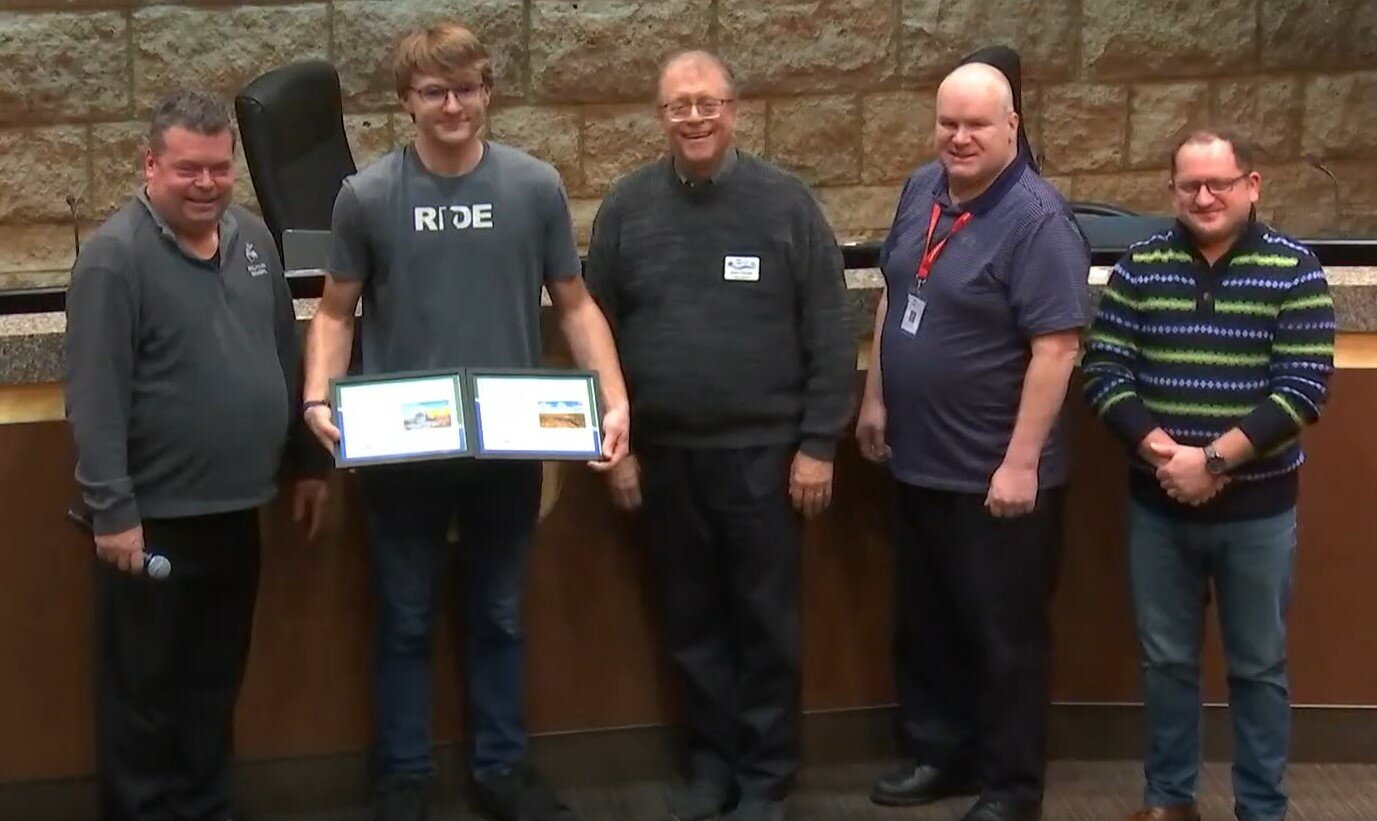 Isaac Pavek accepts an award from the Cottage Grove City Council for winning two categories of submissions in the 2023 photo contest.
