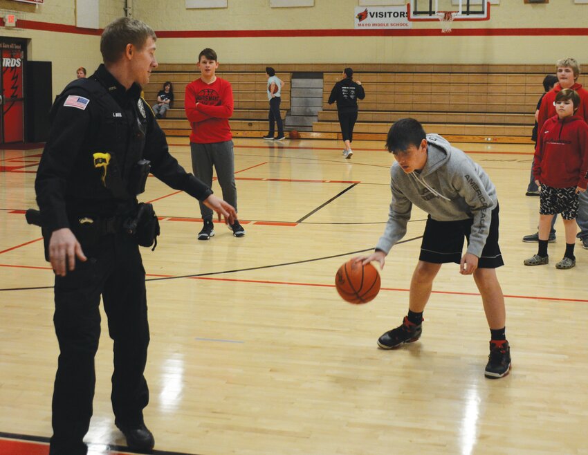 Mayo eighth grader Dylan Lamb looks for a lane to score during a game of one-on-one basketball against Paris Police Officer Logan Bell. School walkthroughs allow officers to build relationships with students and learn the layout of each school.