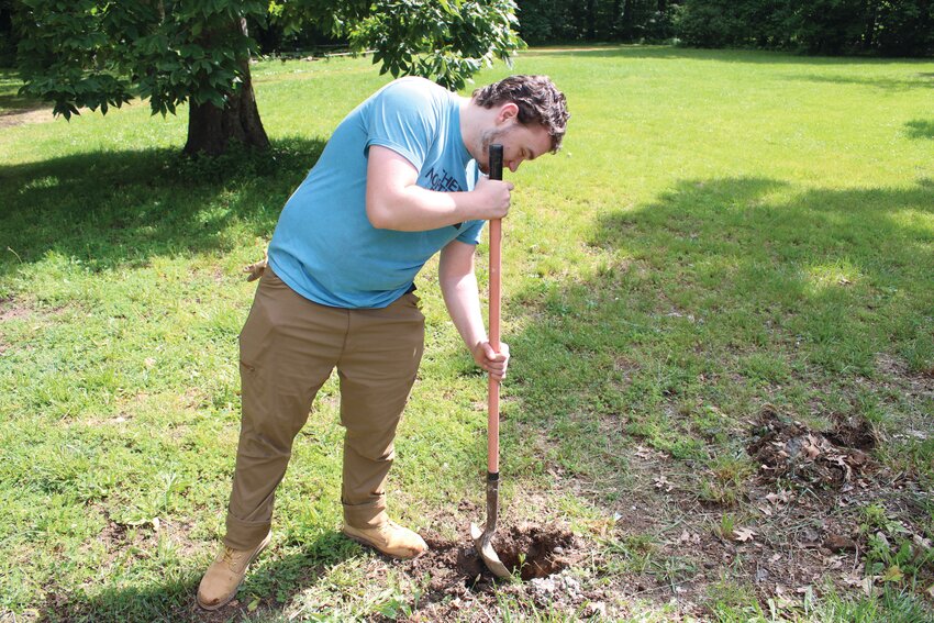 Kalieb Gallagher, who is working towards his Eagle Scout, shovels gravel into the bottom of the a fence post hole before a new one is placed.