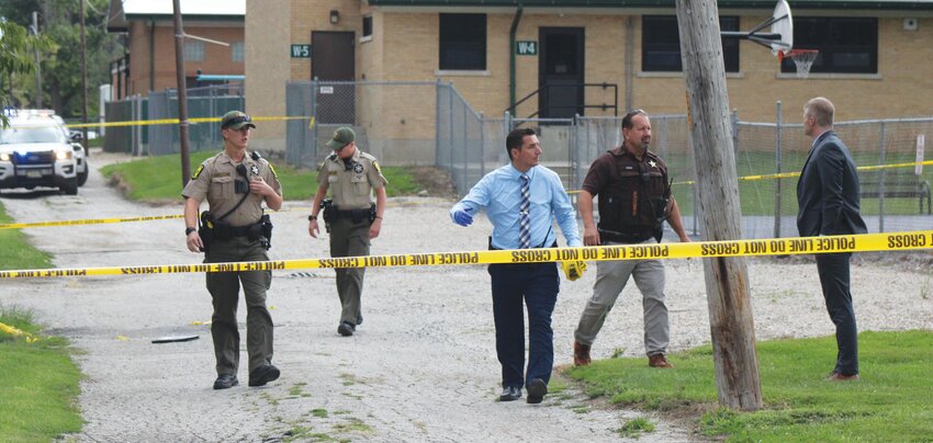 Local law enforcement agents search an alley behind Wenz School in Paris following an early morning incident. Left to right are two Illinois State K9 Troopers, Detective Jacob Jenkins, Sheriff Jeff Wood and Assistant Edgar County States Attorney Phil Dobelstein. The Prairie Press will release updates as they become available.