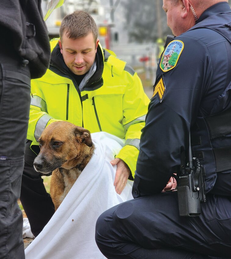 EMS worker Jessie Lewsader (left) and Paris Police Sergeant Chris Ray (right) comfort a dog rescued from a house fire on Jan. 1.