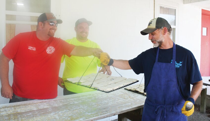 Brocton Fire Chief Kraig Key, left, hands freshly breaded fish to P.J. Bezy, right, of Neptune Foods, for frying at the fire department&rsquo;s annual Jonah Fish Fry as part of the Brocton Springfest. Firefighter Cody Bosh, yellow shirt, was helping with the breading detail.