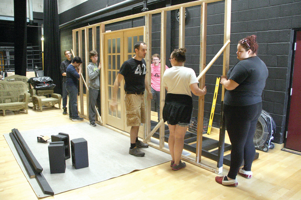 TAKING SHAPE: Richard Denningham (center) instructs the crew in the erection of a wall that serves as a major element to the set.