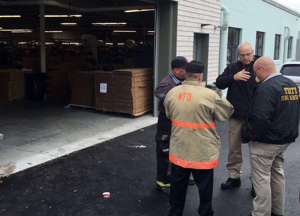 Warren Fire Chief Al Galinelli (in WFD jacket), and fire investigator Vincent Calenda (left) talk with officials from the state fire marshal's office following the explosion at the WaterRower plant shortly before noon Wednesday.