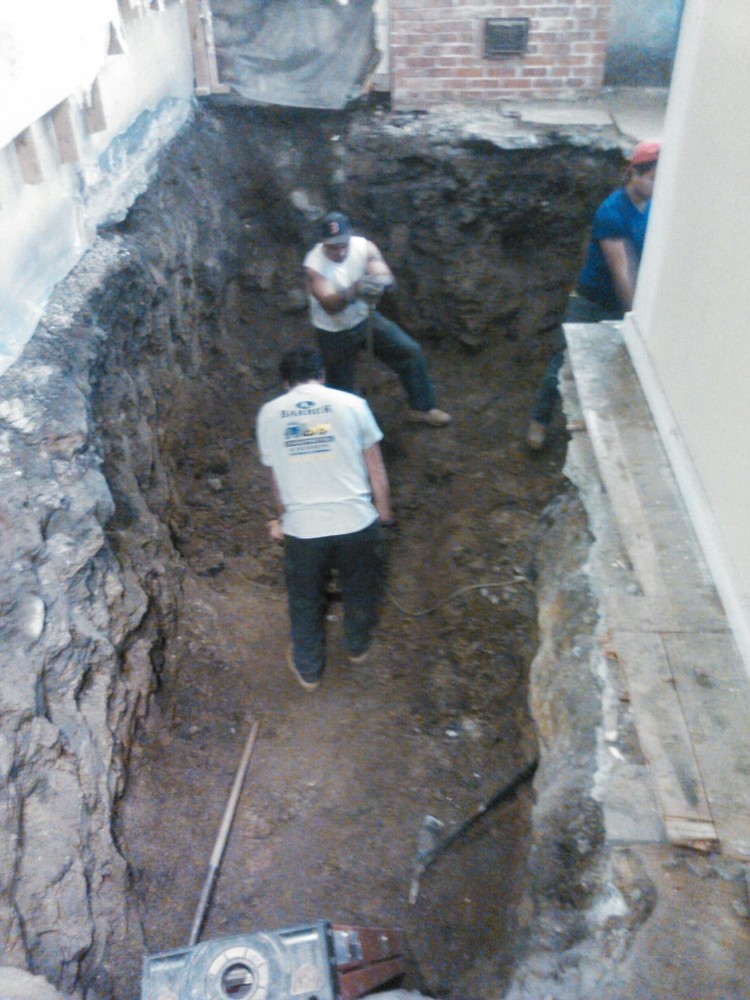 Workers dig out the dentist office cellar by hand to a depth of 12 feet to clean out the spilled heating oil.