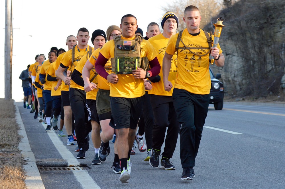 Marine Lance Cpl. Cristian Garcia (left) and Marine PFC Jered Higley (with torch) lead a group of runners along West Main Road in Portsmouth on their way to Newport Monday morning, shortly after the start of the torch run.