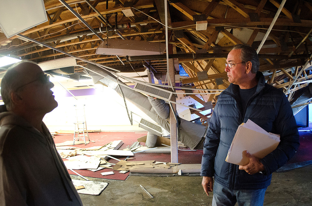 Doug Gablinske (right) and a worker check out the damage caused by the collapsed roof at the Belltower Plaza on Monday.