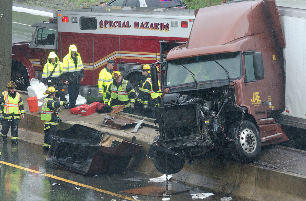 East Providence firefighters work the scene of a tractor-trailer crash on 195 after the broadway exit heading into Providence on Saturday morning. The truck, heading westbound jackknifed and crashed over the median, blocking traffic on both sides of the highway.