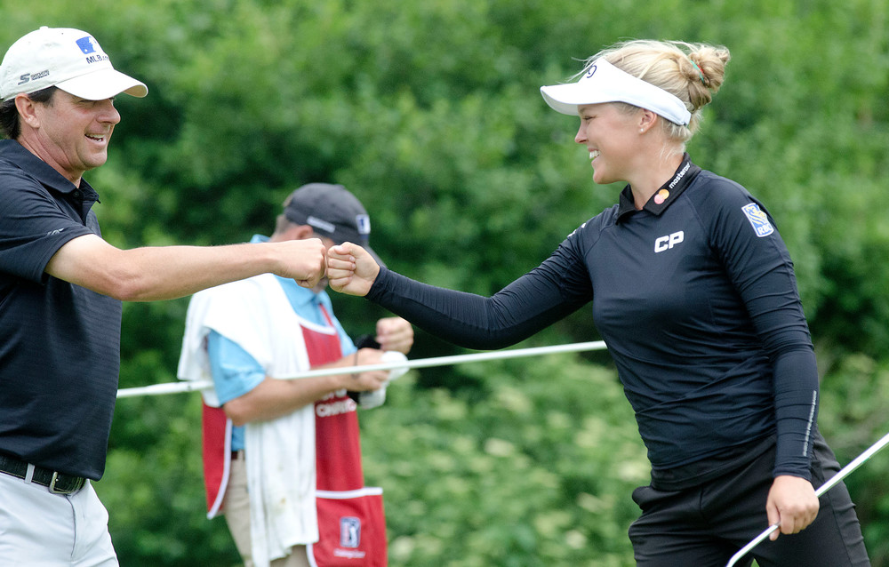 Billy Andrade and teammate Brooke Henderson bump fists after the duo both sank their birdie putts on the 11th. The team including Keegan Bradley won the one day tournament.