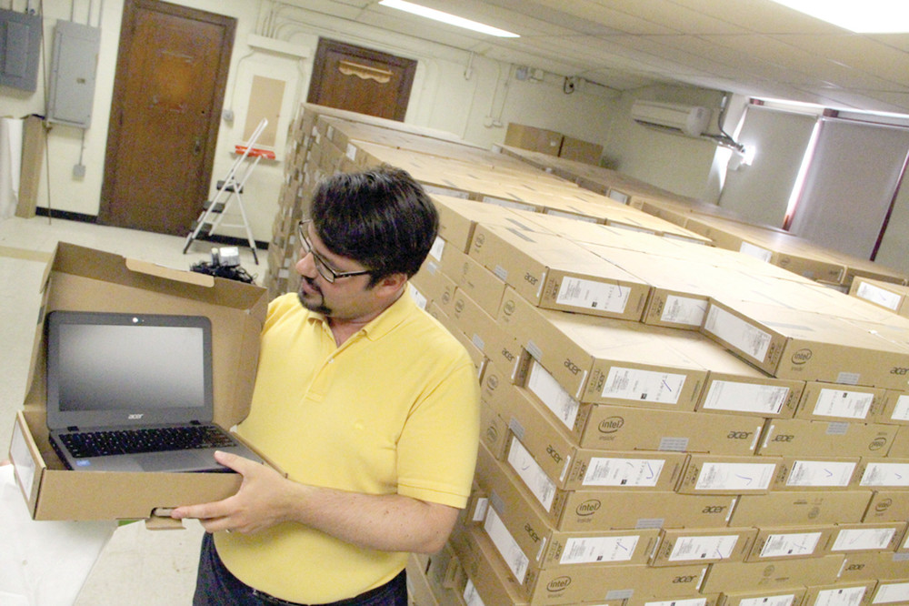 PROGRAMMED AND READY: A total of 1,200 Chromebook computers, boxed, fully charged and programmed are ready to be distributed to students and teachers. Displaying one of the units is Warwick School District&rsquo;s Director of Technology, Douglas Alexander.