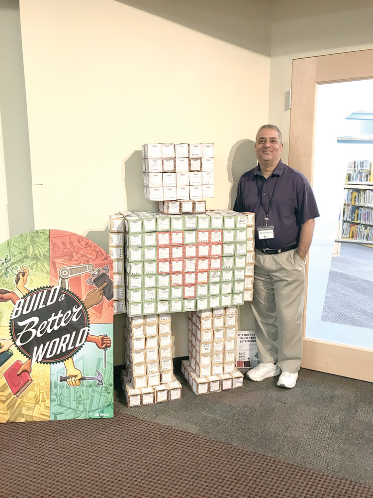 BUILDING A FRIENDSHIP: Director of Cranston Libraries, Ed Garcia poses with &quot;Roz&quot; the robot built out of reading cubes submitted by Cranston children who participated in the summer reading program Building a Better World.
